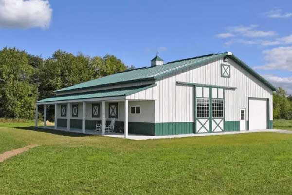 Newly built white pole barn with a green roof