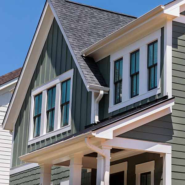 Mid-class, two-story home with green siding and gray shingles on its roof